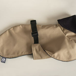 kurtka dla psa whippet. Jest przeiwdeszczowa, beżowa z wierzchu i podszyta czarnym polarkiem od dołu, zapinana na plastikową klamrę na plecach i posiada składany kaptur.